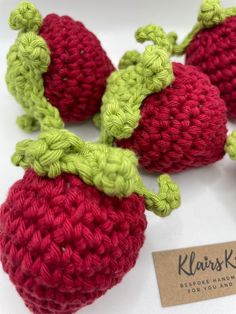 crocheted strawberries are displayed on a white surface with a business card in the foreground