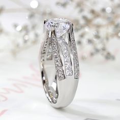 a close up view of a diamond ring on a white surface with diamonds in the background