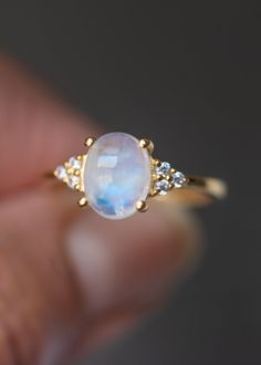 Our Fleur Moonstone ring features a single blue flash Moonstone set in a sturdy four-prong setting surrounded with three white topaz on each side. It can be worn as an engagement ring and a statement ring stacked with our Colline and Hana ring for a unique look. Always handmade with genuine and natural stones on solid sterling silver and thick gold vermeil that will stand the test of time. D E T A I L S * Materials - 18k gold vermeil on solid 925 sterling silver, genuine blue flash Moonstone * G Modern Moonstone Rings As Gift, Modern Moonstone Rings For Gifting, Modern Moonstone Rings For Gifts, Modern Moonstone Birthstone Ring For Gift, Modern Moonstone Birthstone Ring Gift, Minimalist Moon-shaped Moonstone Ring As Gift, Modern Moonstone Ring As A Gift, Minimalist Moonstone Ring In Moon Shape, Modern Moonstone Ring Gift