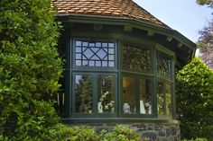 a gazebo in the middle of some bushes and trees with windows on each side