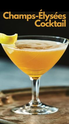 a close up of a drink in a wine glass on a tray with a lemon wedge