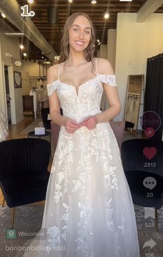 a woman standing in front of a mirror wearing a white dress with flowers on it