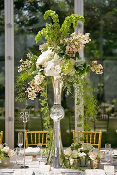 a tall glass vase filled with flowers on top of a table