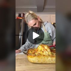 a woman is making a pizza with cheese and sauce on the table in front of her