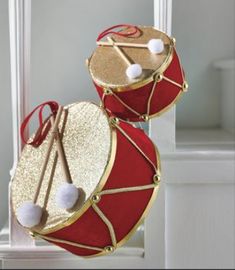 two red and gold drum cases with pom - poms hanging from the sides