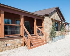 a house with stone and wood sidings on the front porch, stairs leading up to it