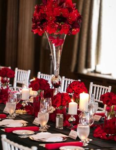 a table set with red flowers and candles for a formal dinner or wedding reception at the same time