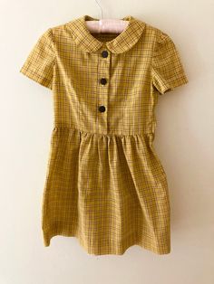 "Absolutely perfect cotton day dress with Peter Pan collar. It is so sweet on; Rumpus Room is sad to see it go! This beauty is handmade, but fits best for a modern size 5 or 6.  Measures: 13\" at chest 12\" at waist 26\" in length In excellent vintage condition, with no rips, stains, tears, holes, or other defects.  A true gem!" Fitted Doll Collar Dress For School, Spring School Dress With Collar, Collared Spring Dresses For School, Casual Cotton Dress With Peter Pan Collar, Vintage Dresses For School In Spring, Classic Cotton Dress With Buttons, Classic Cotton Dresses With Buttons, Retro Short Sleeve School Dresses, Retro Cotton Plaid Dress