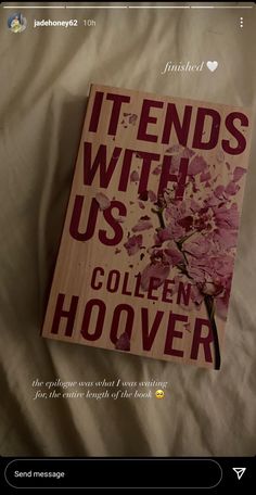 a book sitting on top of a bed next to a white sheet with pink flowers