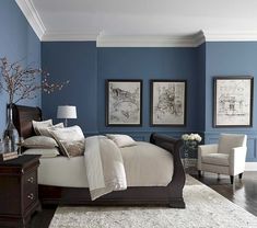 a bedroom with blue walls and white carpeted flooring, two framed pictures on the wall