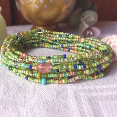 three strands of glass beads are sitting on a table next to a vase and bowl