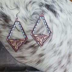 a pair of brown and white earrings on top of a horse's fur covered head