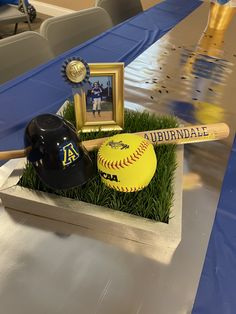 a baseball bat, helmet and ball sitting on top of some grass in front of a table