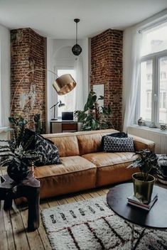 a living room filled with lots of furniture next to a window covered in plants and potted plants