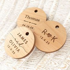 three personalized wooden tags with names and date engraved on them, sitting on a white blanket