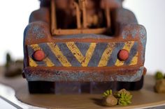 a close up of a toy train on a table with rocks and plants around it