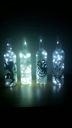 three bottles with lights in them sitting on a table next to each other and one has a game of thrones logo on it