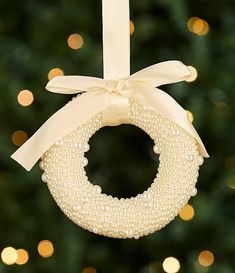 a christmas ornament hanging from the side of a tree with lights in the background