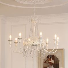 a chandelier hanging from the ceiling in a room with white walls and trimmings