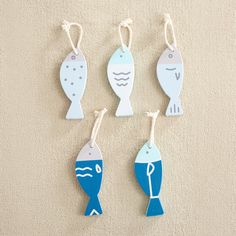 four wooden fish ornament hanging from strings on a beige surface with white and blue colors