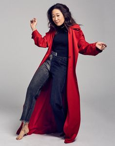 a woman in a long red coat is posing for a photo with her legs spread out