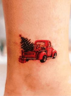 an old fashion red truck with a christmas tree on the back of it's leg