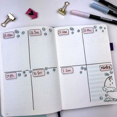 an open planner with stickers on it next to some pens and pencils in the background