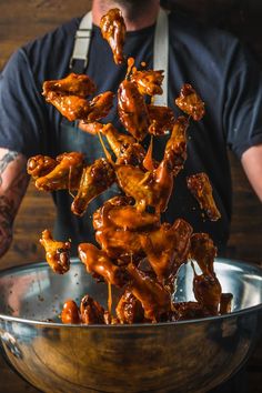 the man is pouring sauce on chicken wings