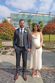 a man and woman standing next to each other in front of a glass walled building