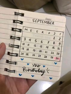 someone is holding up a planner with the date for their birthday written on it in black ink