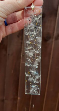 a hand holding a clear tube with dandelions in it