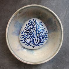 a blue and white bowl with a leaf design on the inside is sitting on a gray surface