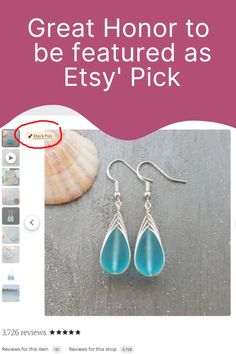 a pair of blue teary earrings sitting on top of a table next to a seashell