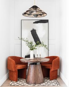 a dining room table with two chairs and a plant in the center, on top of a rug