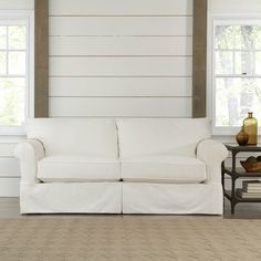 a white couch sitting in front of two windows