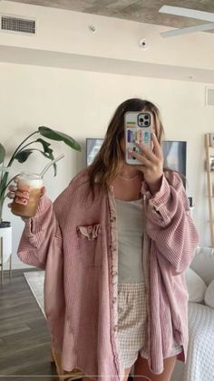 a woman taking a selfie with her cell phone and holding a glass of coffee