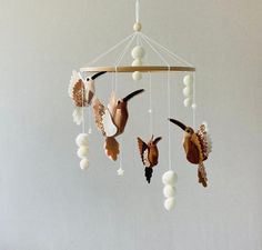 a mobile with birds and shells hanging from it's sides on a white wall