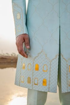 Powder blue full sleeve sherwani hand embroidered with gold khidki applique motifs and embellished with cutpipe work. Paired with pant pyjama.
Components: 2
Pattern: Embroidery, Embellished
Type Of Work: Thread, cutpipe
Neckline: Mandarin collar
Sleeve Type: Full sleeves
Fabric: Sherwani: Chanderi Silk, Pant Pyjama: Vegan Silk
Color: Blue
Other Details: 
Pleated collar
Disclaimer: The fabrics used, are handwoven, hence may have impurities or slubs/variation in the weave that beautifies the look Kurta Designs Men's, Nav Durga, Blue Sherwani, Indian Groom Wear, Fashion Models Men, Men Kurta, Mens Fashion Illustration, Wedding Outfit Men, Designer Suits For Men