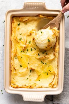 someone scooping mashed potatoes into a casserole dish