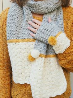 a woman wearing a knitted scarf and mittens with her hands on her chest