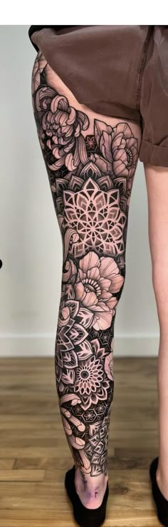 a woman's legs with tattoos on them and flowers in the bottom right leg