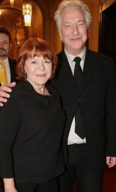 two people standing next to each other wearing suits and ties