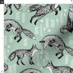 a green background with black and white foxes on the same fabric as it appears in this image