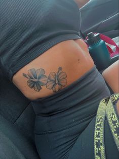 a woman's lower back tattoo with flowers on her left side ribcage