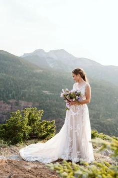 a woman standing on top of a mountain holding a bouquet