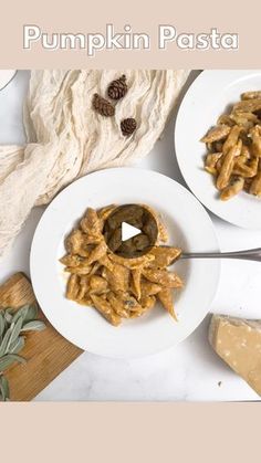 two white plates topped with pasta next to cheese and pine cones on top of a wooden cutting board