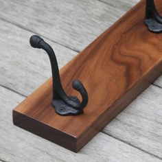 a pair of black iron hooks sitting on top of a wooden board