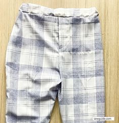 a pair of blue and white checkered pants sitting on top of a wooden floor