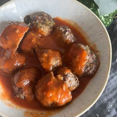 a white bowl filled with meatballs and gravy on top of a table