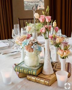 a table topped with books and vases filled with flowers